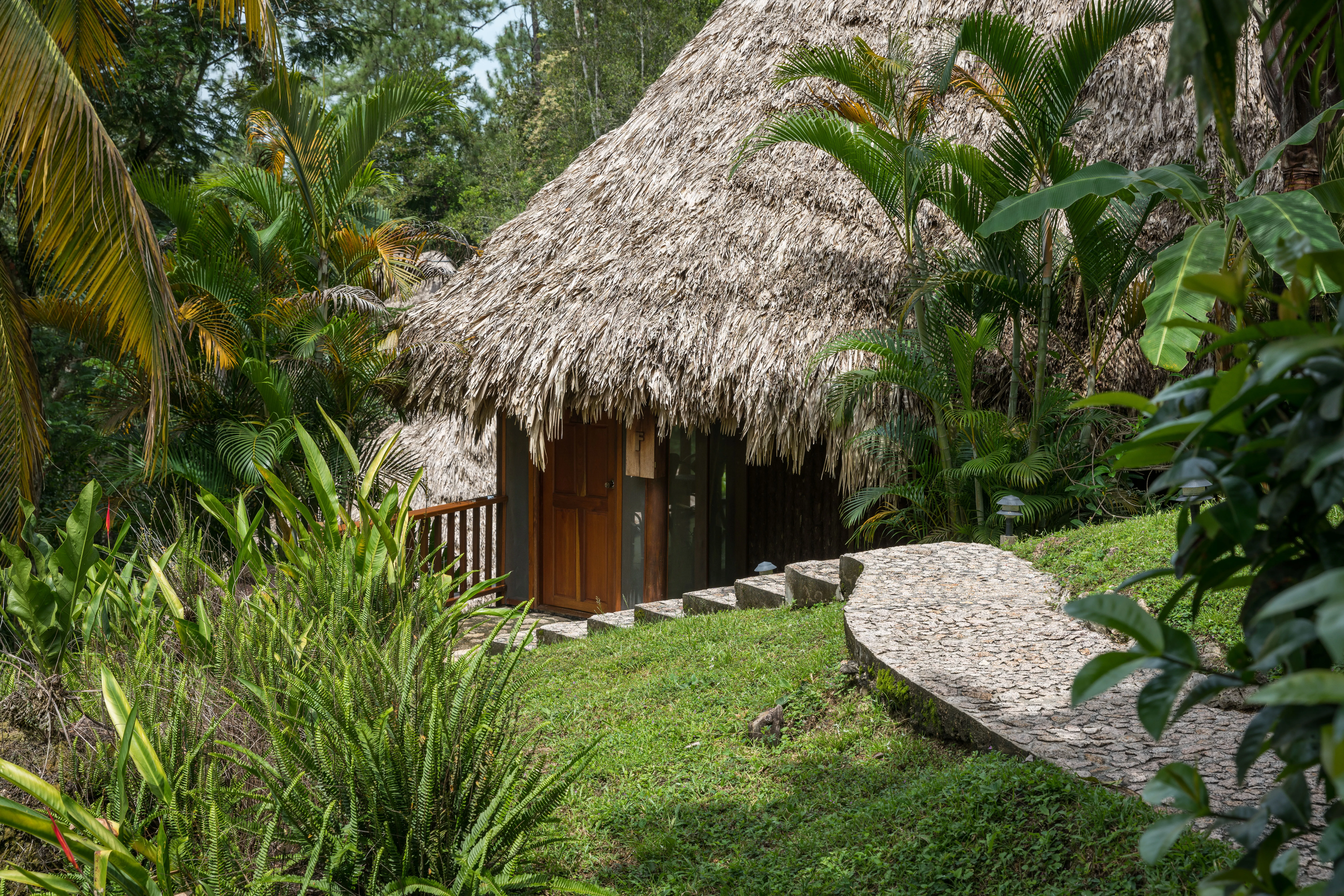 Family cabana exterior with thatched roof and stone walkway