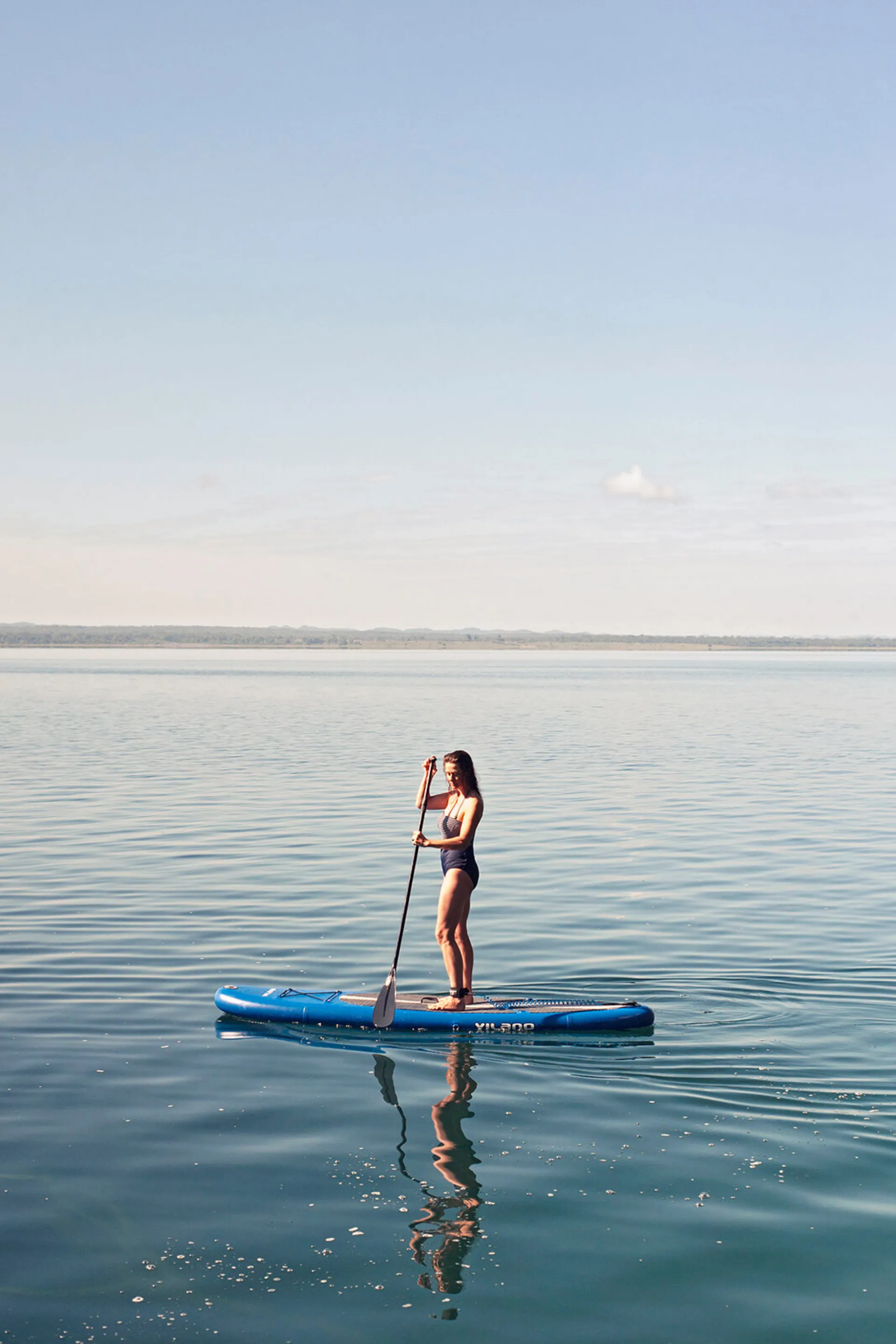 A patron of La Lancha paddle-boarding on the lake.