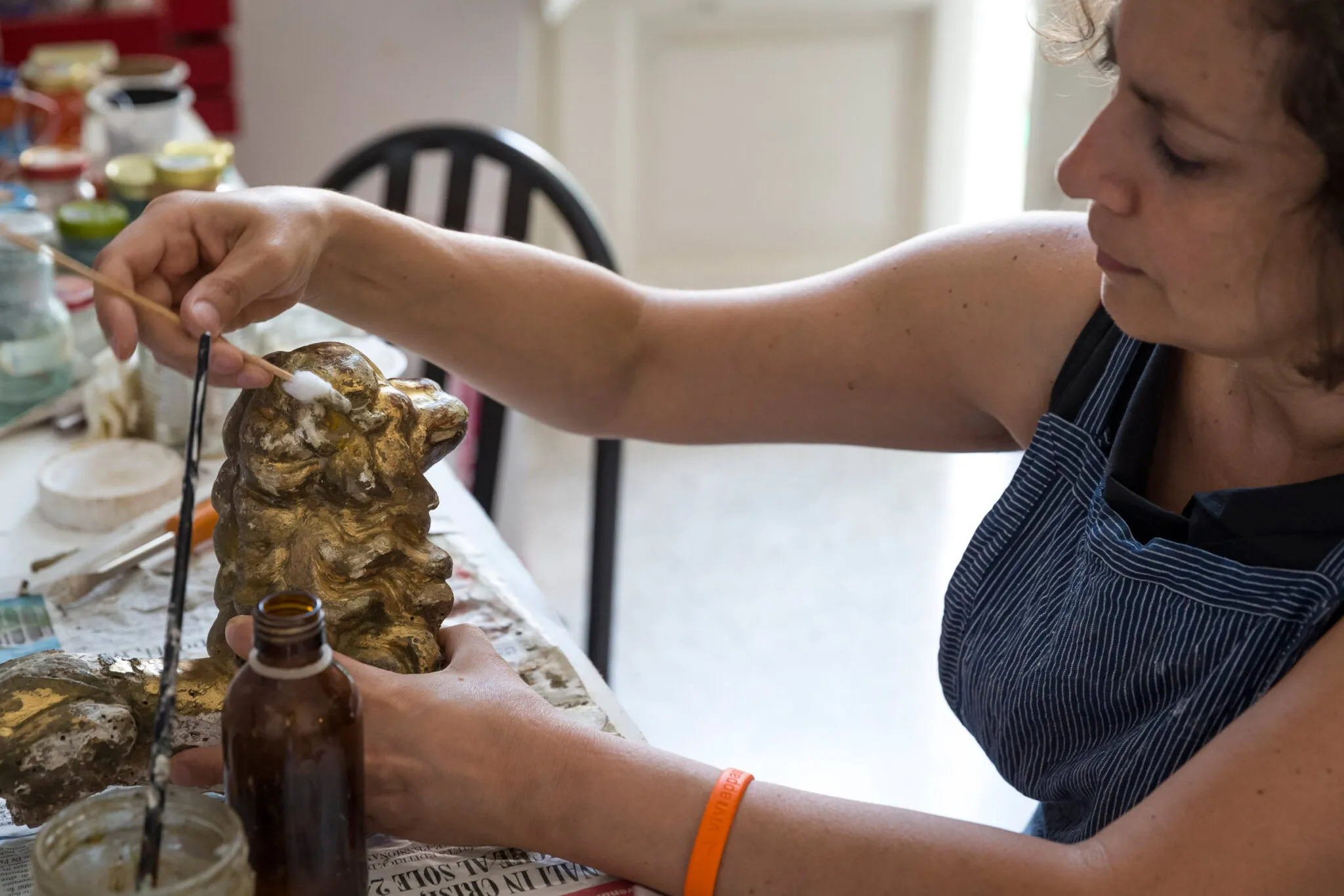 An artisan cleaning a small sculpture