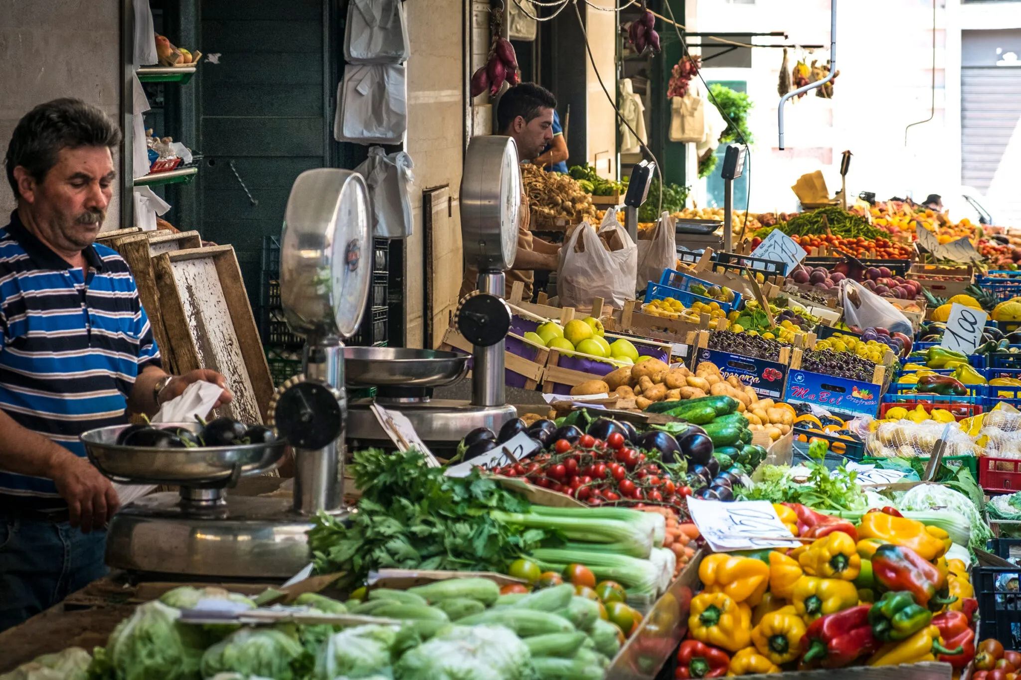 Men sell produce at an open air market