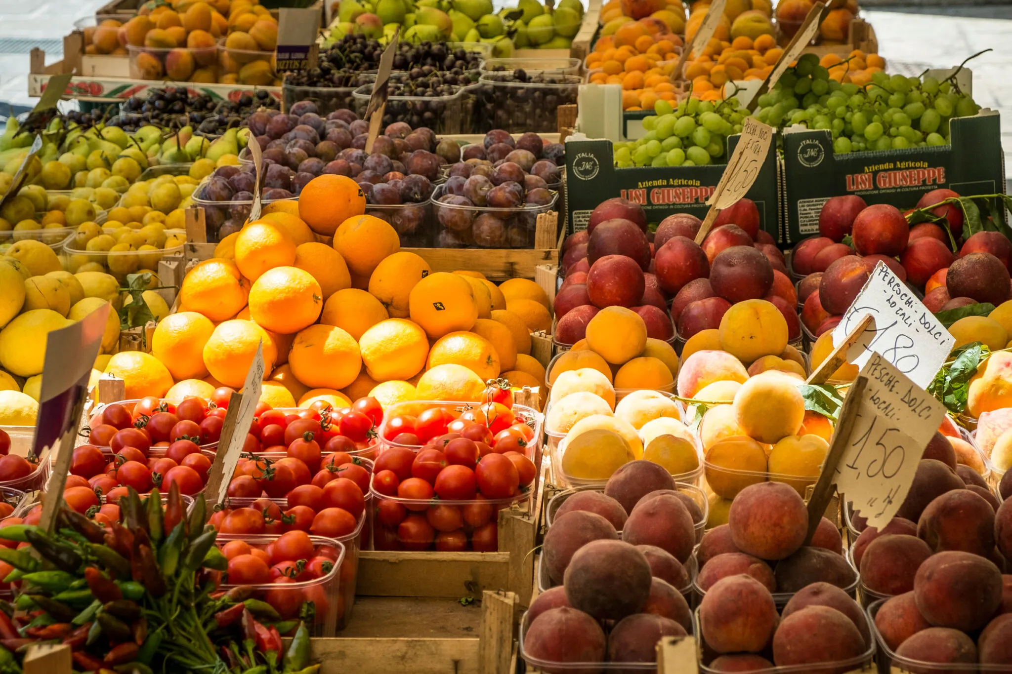 Plums, oranges, peaches, tomatoes and grapes for sale at a farmers market
