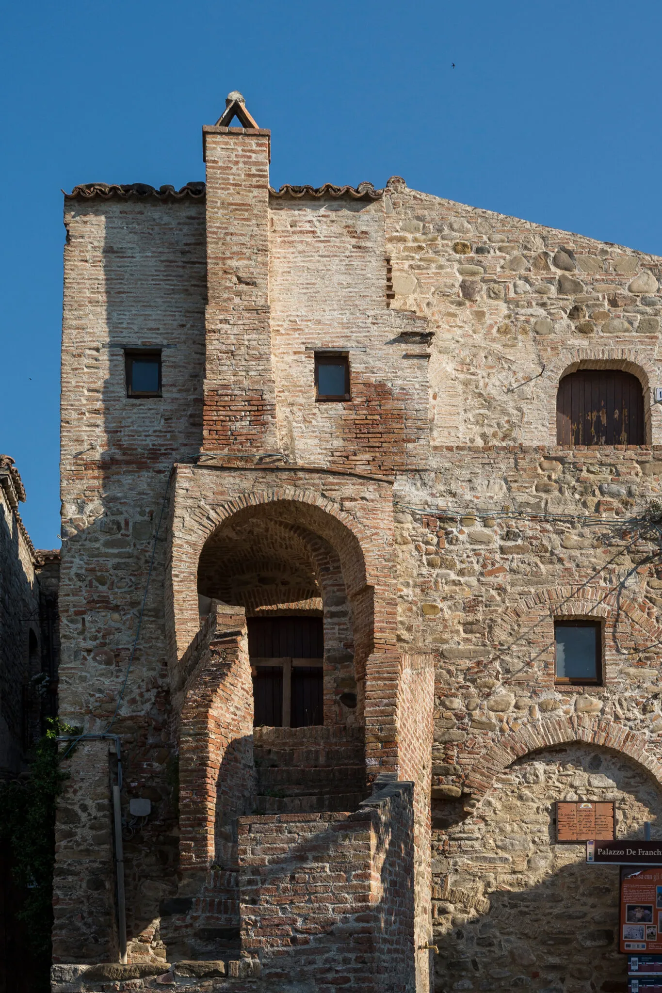 Stone and brick building with arches and a crooked stairway