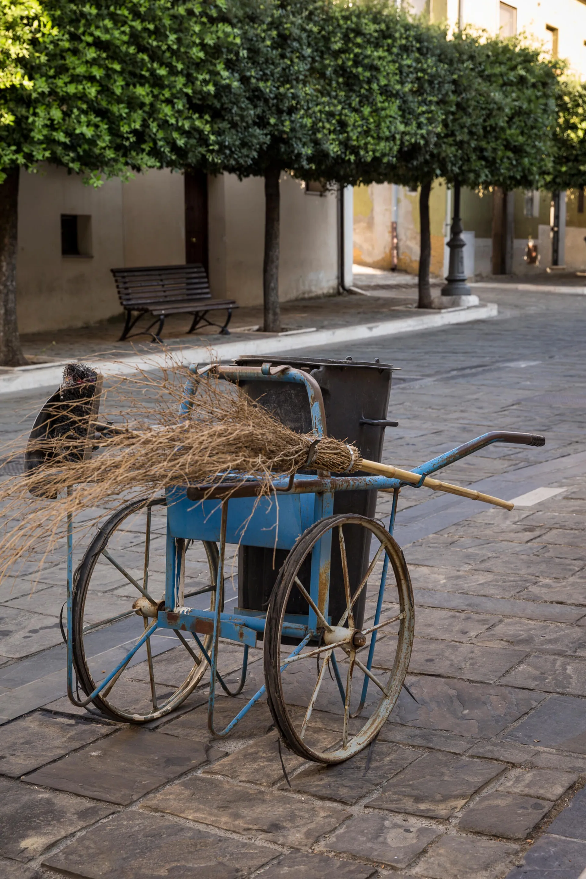 A blue metal cart with wheels on the street in Aliano