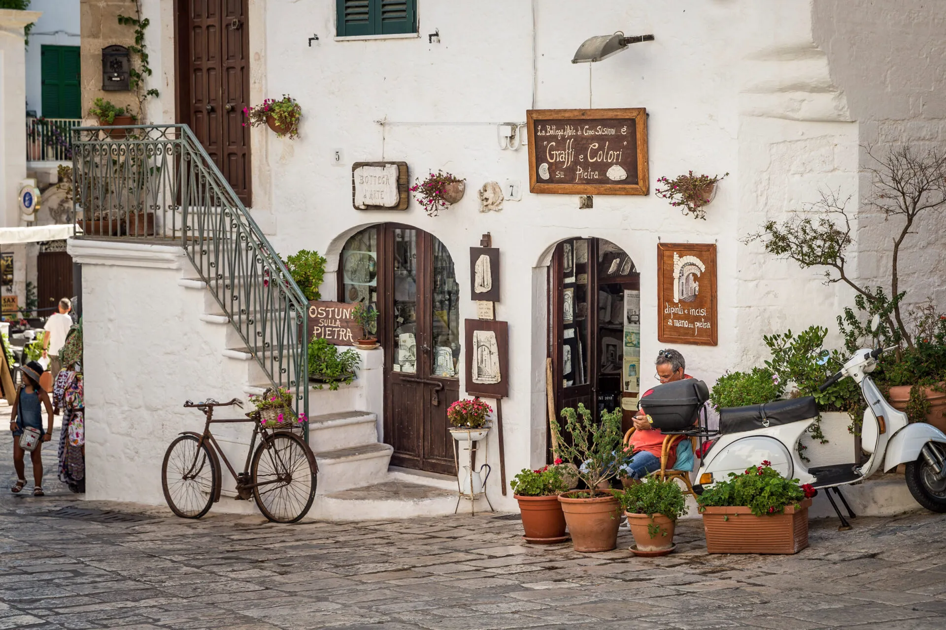 A man outside of a shop next to a vespa