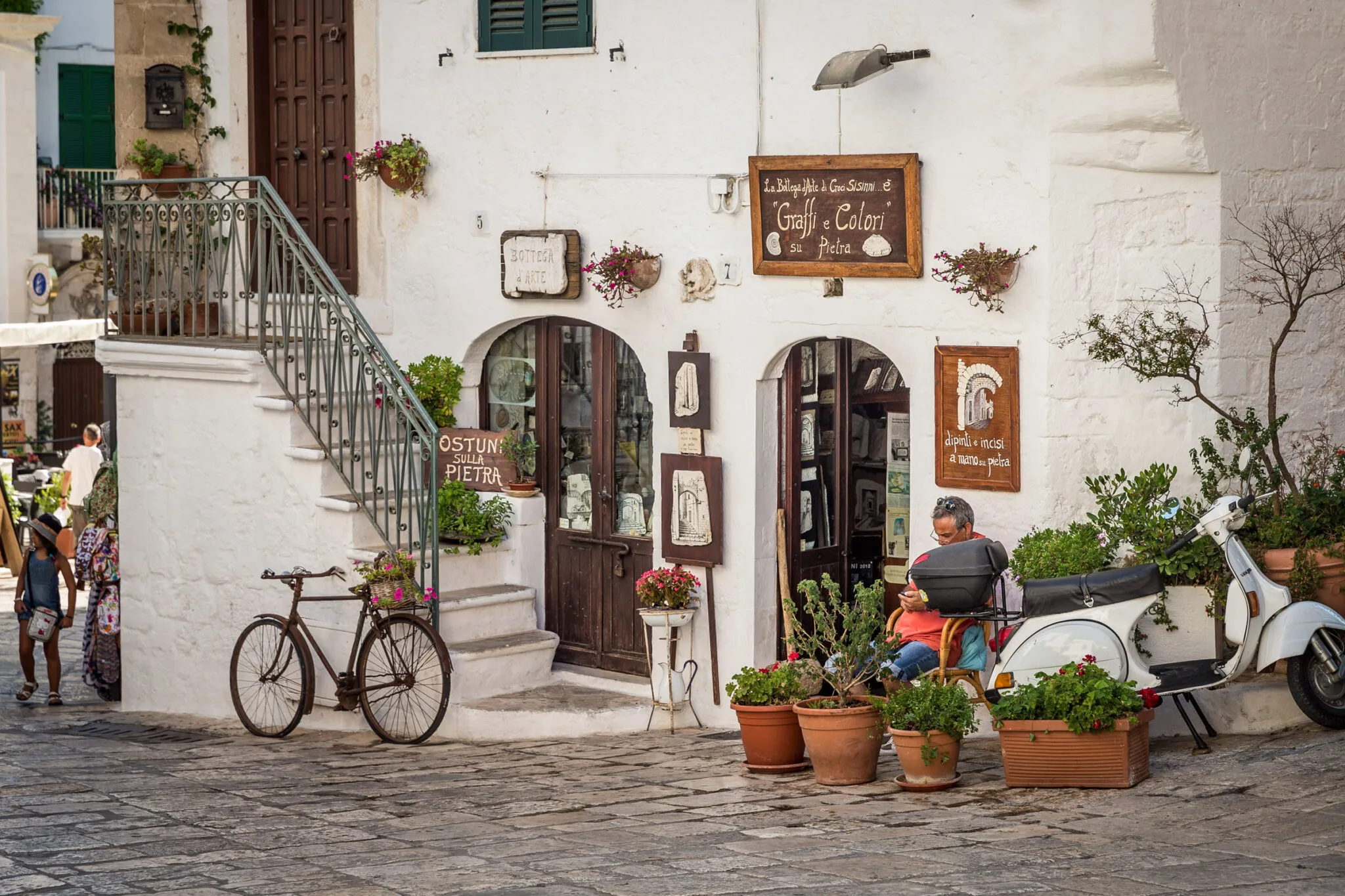 A man outside of a shop next to a vespa